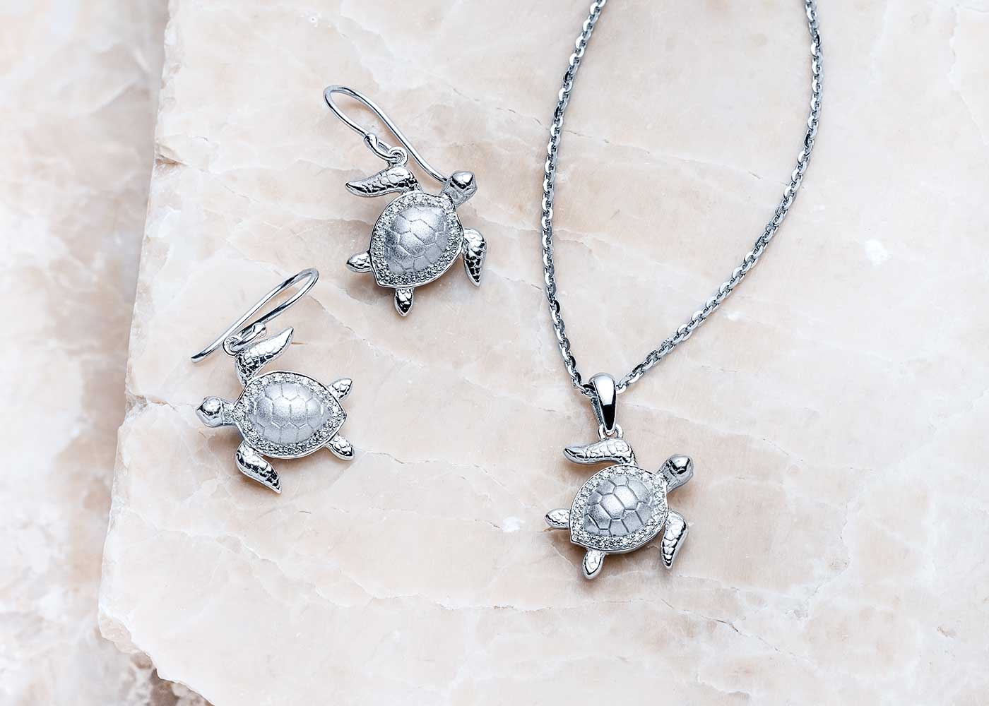 A Landing Company Radiant sea turtle pendant resting on natural stone — a quiet symbol of protection