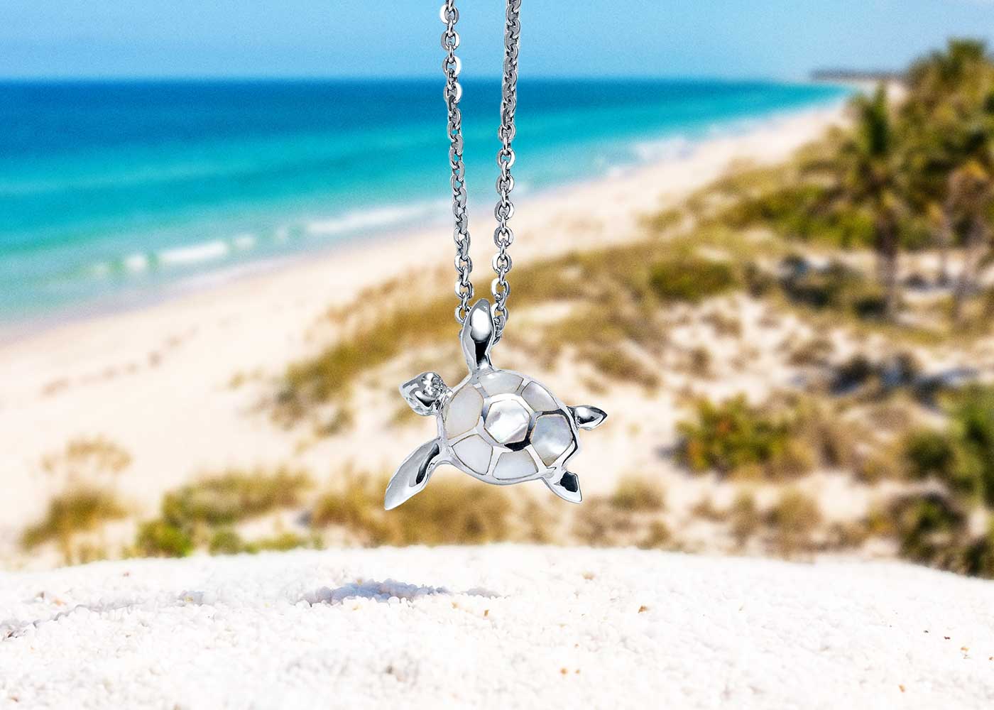 A Landing Company sea turtle necklace photographed on the Florida coast — a symbol for the journey home